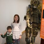 kids standing next to soldier manekin