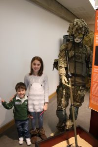kids standing next to soldier manekin