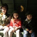 3 kids wearing army uniform and helets inside model aircraft