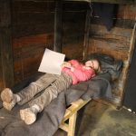 lois laying on a wooden bed in the trench