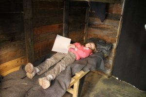 lois laying on a wooden bed in the trench