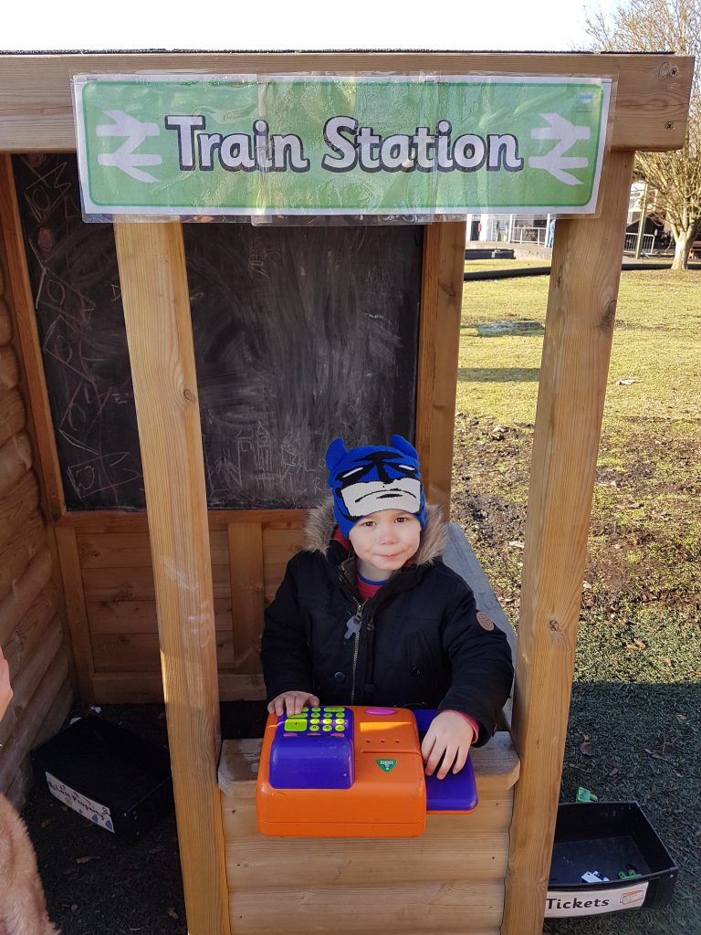 cody playing in the wooden pretend ticket booth