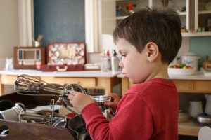 Boy playing with kitchen utensils in the old kitchen
