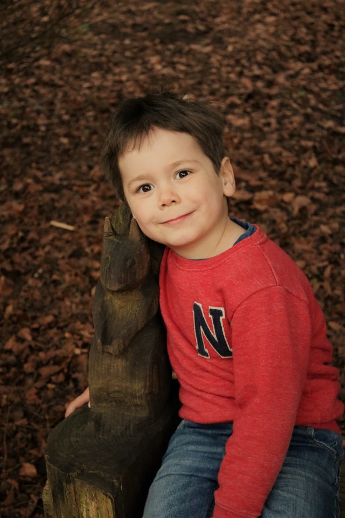cody sat on bench in forest next to wooden carved bunny