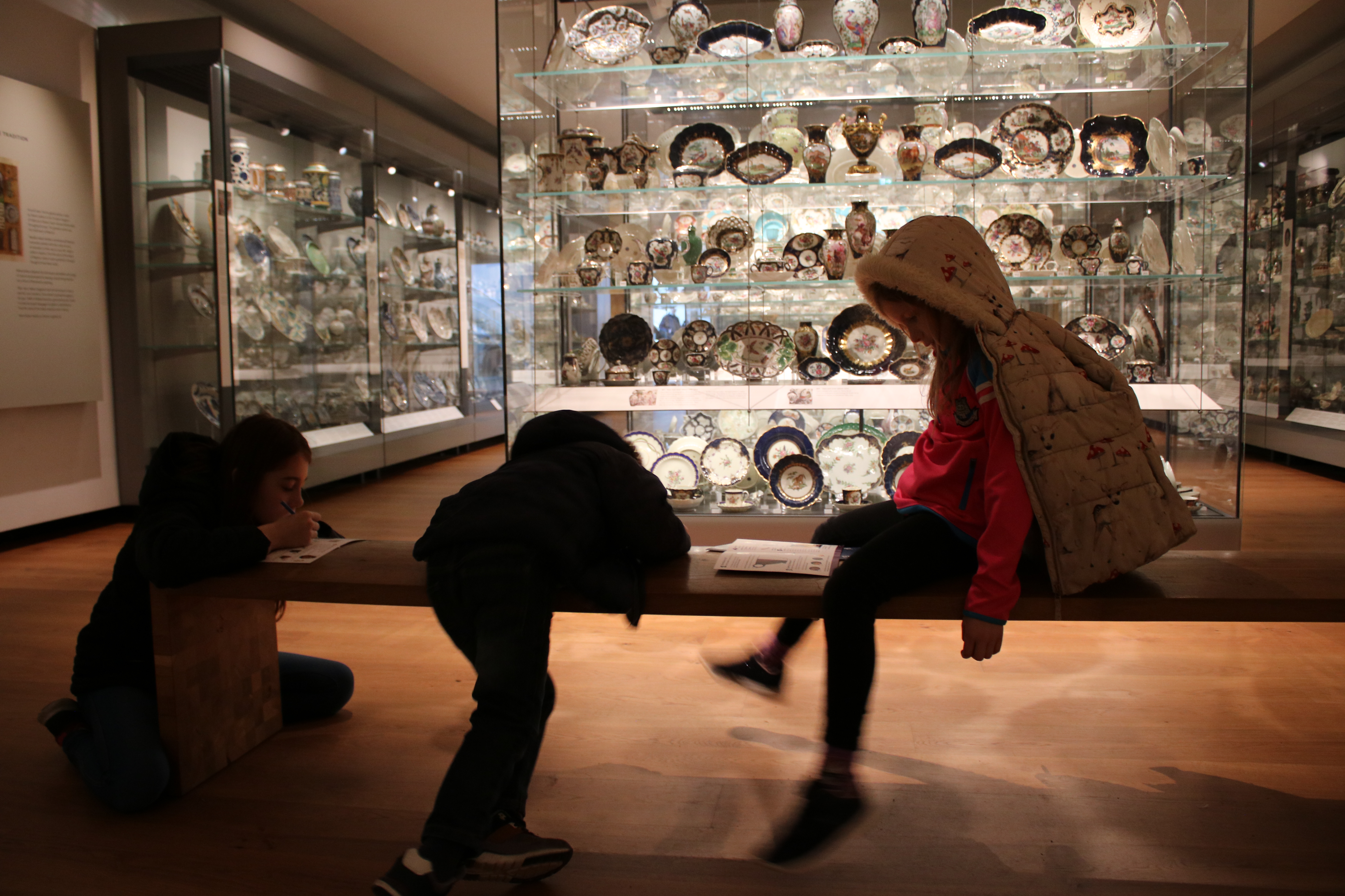 kids sat on a bench in the china gallery on a rainy day in Oxfordshire