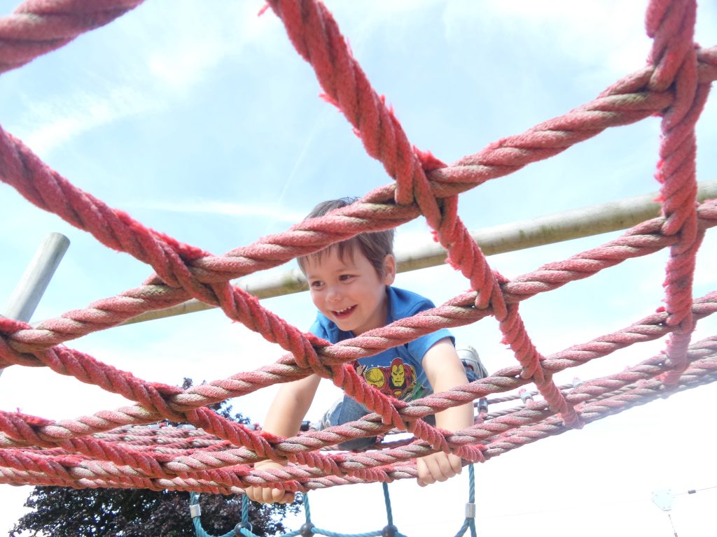 Cody climbing on a cargo net at the park