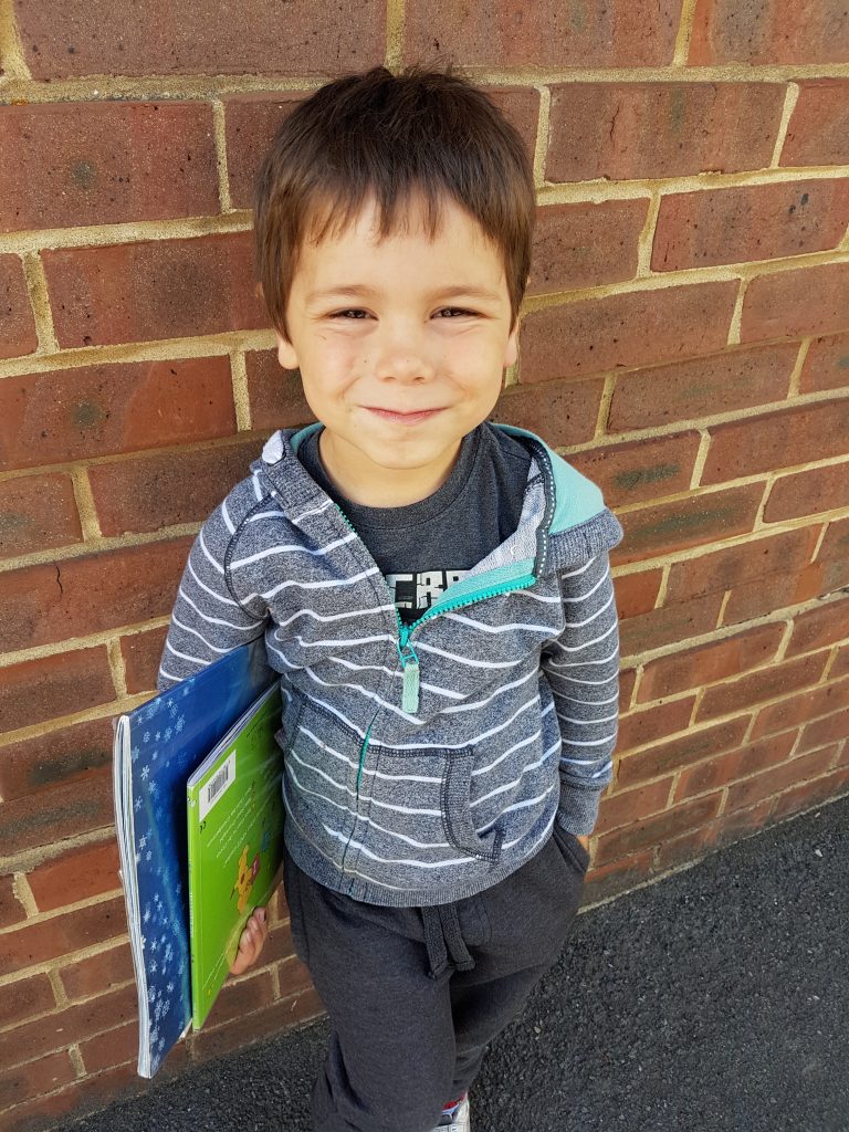 Boy leaning against the library wall holding his books