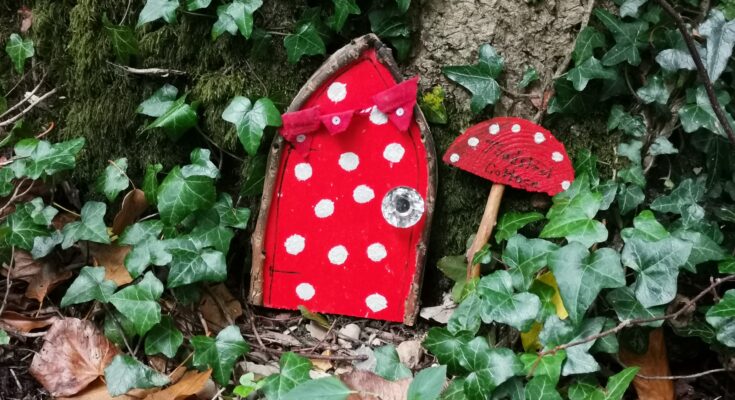 Red spotty fairy doors with toadstool sign next to it