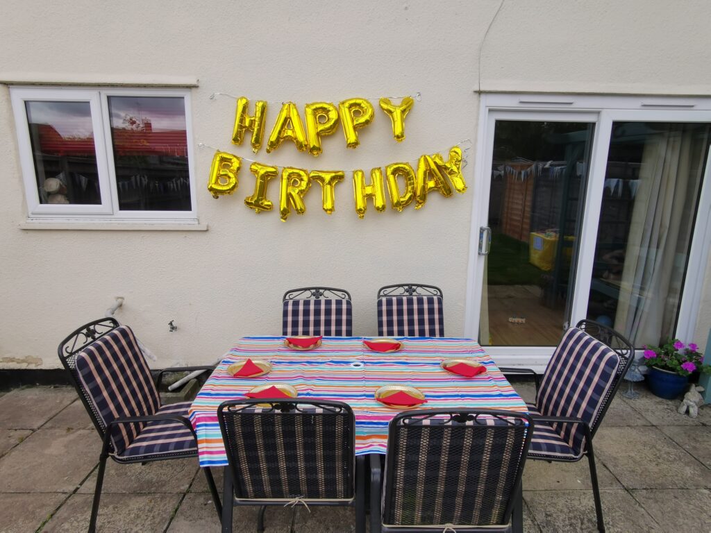 happy birthday balloon banner above garden table