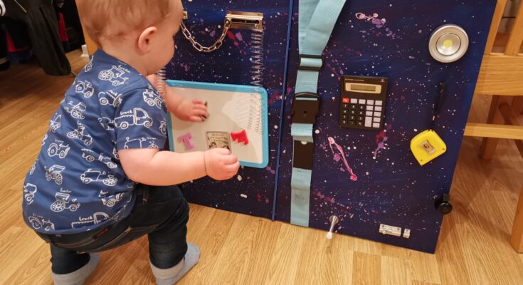 Toddler playing with busy board