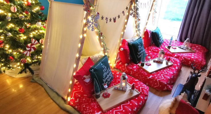 3 teepees set up in living room with red throws, cushions and wooden trays on the mattresses