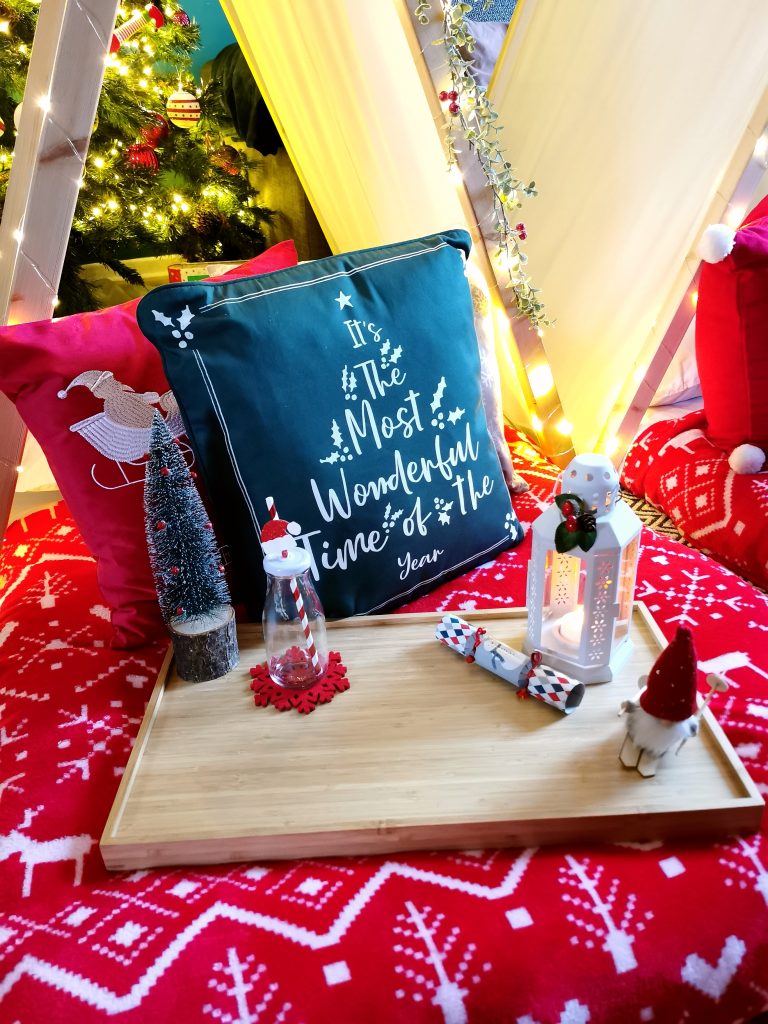 Wooden tray on bed with cushions behind it and decorations on it
