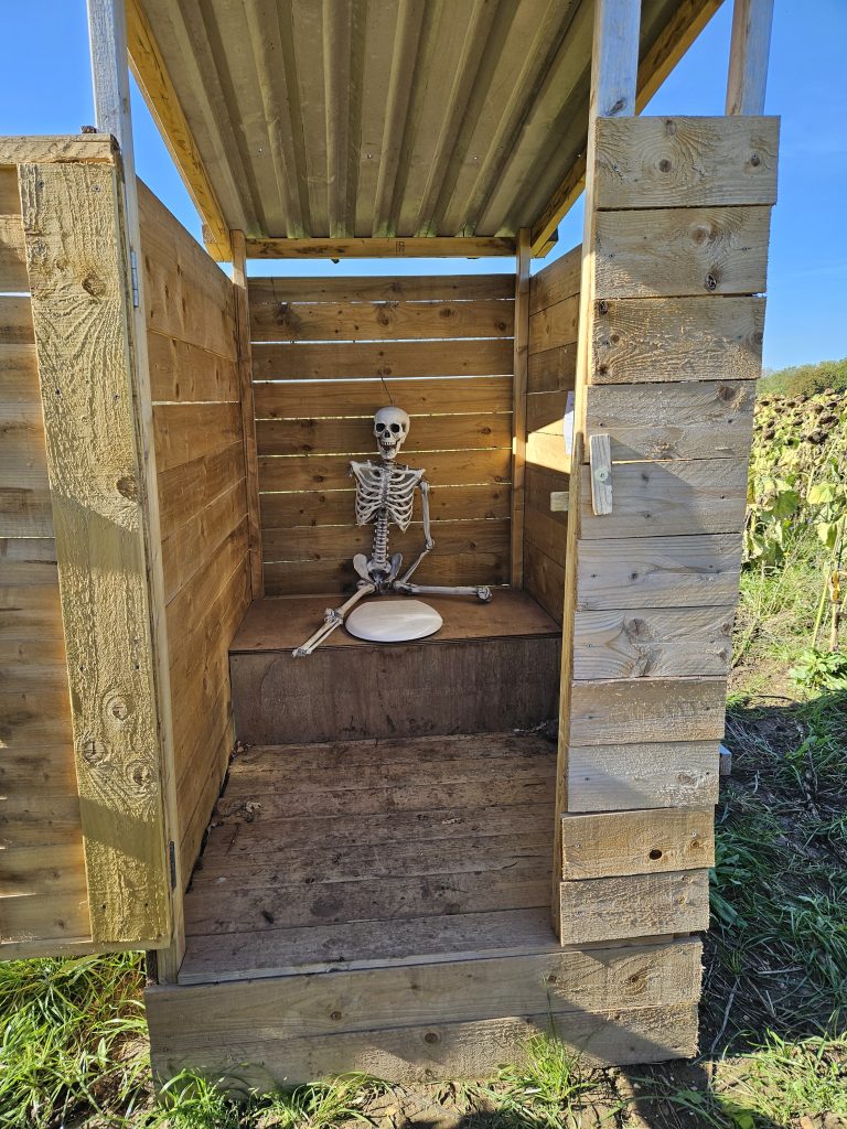 Skeleton sat on the toilet in wooden shed