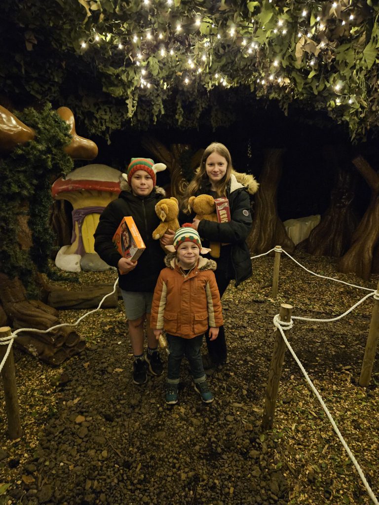 3 children stood in enchanted forest holding teddy bears