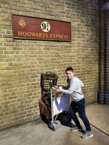 Boy pushing luggage trolley through wall on train platform