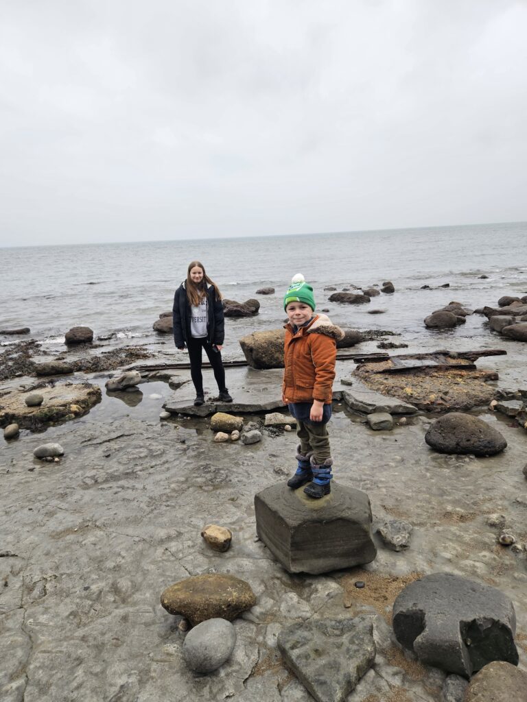two children stood on rocks on the beach