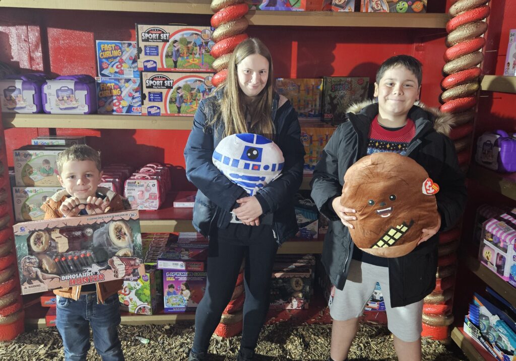 Children stood in front of toy shop shelves holding toys