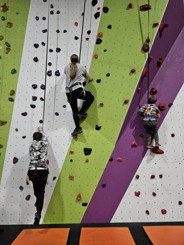 Three children on traditional style climbing wall at Clip n Climb Reading 